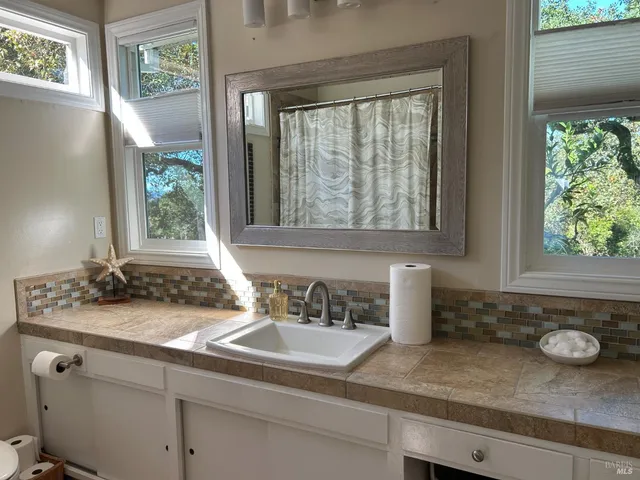 a bathroom with a granite countertop sink and a window