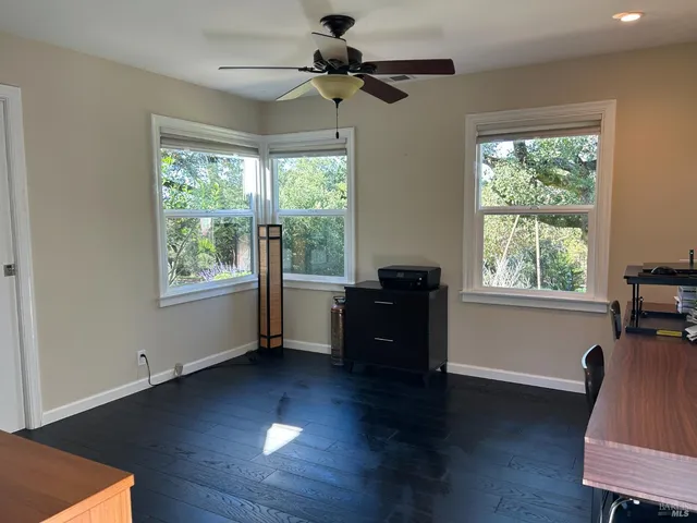 a view of a room with wooden floor a ceiling fan and a window