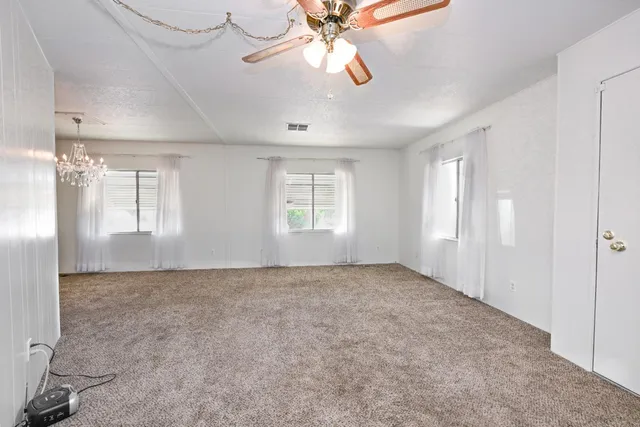 a view of a livingroom with a chandelier fan and kitchen view