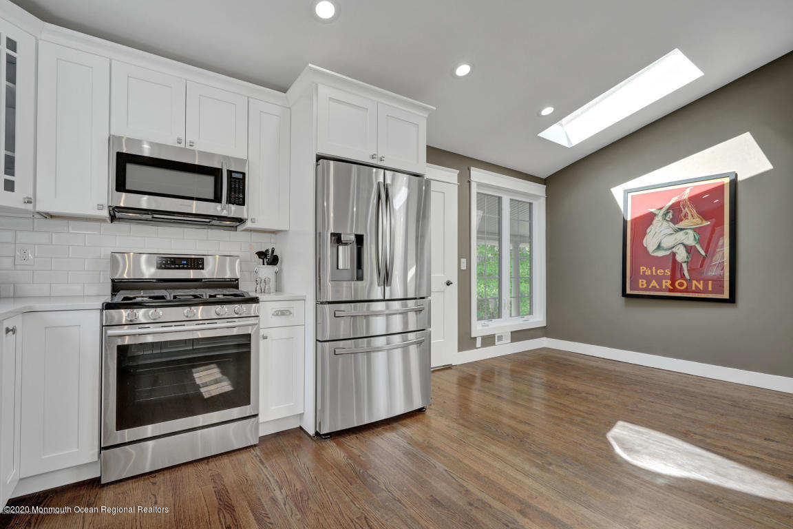 236 Holland Road Holmdel, NJ 07733 - Photo 14 of 42 a kitchen with stainless steel appliances a stove a microwave and white cabinets