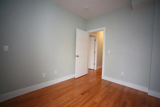 a view of an empty room with wooden floor and closet