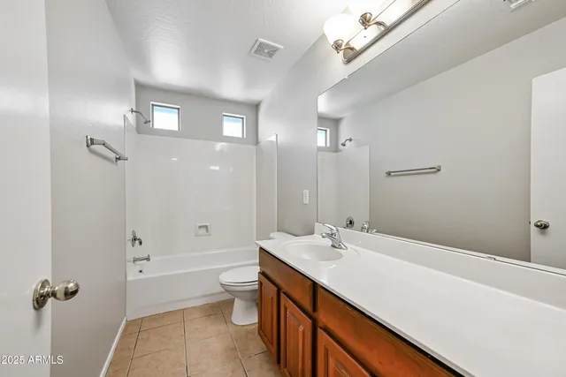 a spacious bathroom with a double vanity sink toilet mirror and bathtub