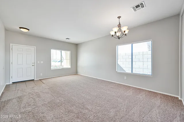 an empty room with windows and chandelier fan