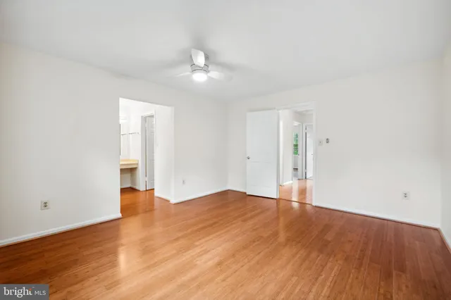 an empty room with wooden floor and ceiling fan