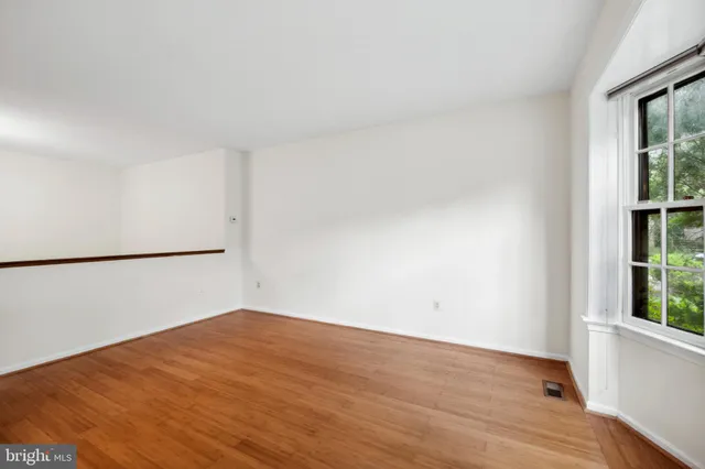 an empty room with wooden floor and window