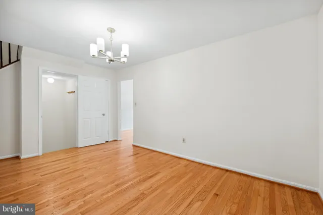 a view of an empty room with wooden floor and a chandelier