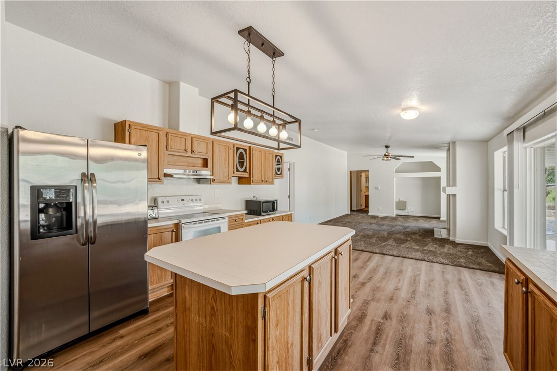 1890 West Dyer Road Pahrump, NV 89048 - Photo 3 of 40 This kitchen features wood cabinetry, modern appliances, and an island, opening to a spacious living area.