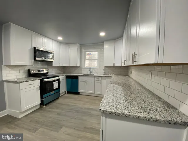 a kitchen with granite countertop white cabinets and stainless steel appliances