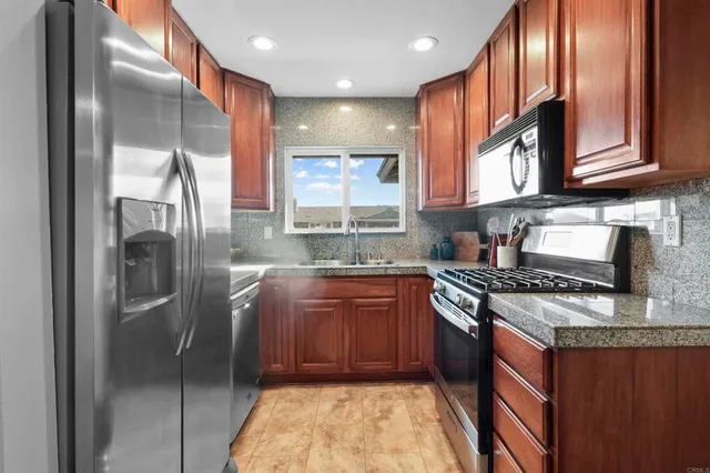 a kitchen with stainless steel appliances granite countertop a sink stove and refrigerator