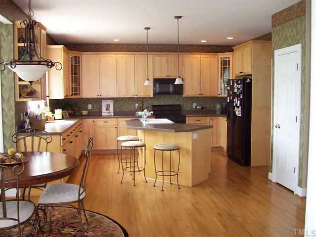 435 Competition Raleigh, NC 27603 - Photo 3 of 5 a kitchen with stainless steel appliances kitchen island granite countertop a refrigerator a stove a sink dishwasher with a dining table and chairs with wooden floor