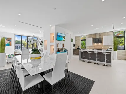a living room with stainless steel appliances granite countertop a couch and a dining table with granite countertop wooden floor