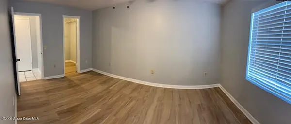 a view of an empty room with wooden floor and a window