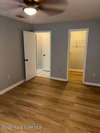 an empty room with wooden floor closet and chandelier fan