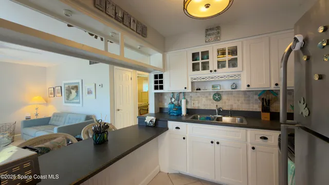 a kitchen with stainless steel appliances granite countertop a refrigerator a sink dishwasher and white cabinets next to a window