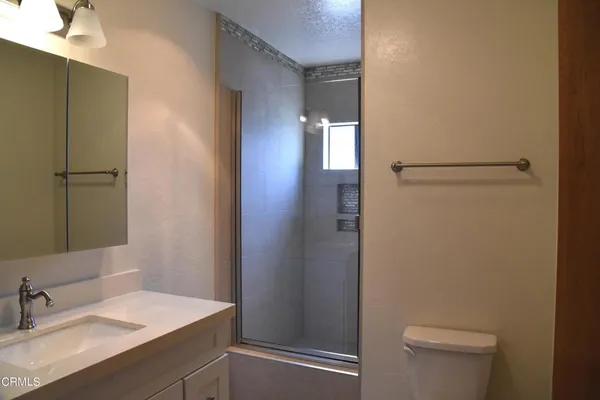 a bathroom with a sink a toilet a shower and a mirror