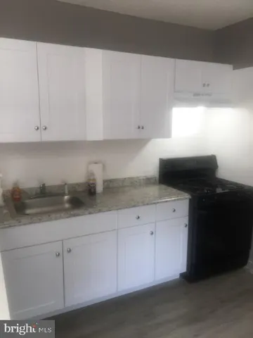 a kitchen with granite countertop white cabinets and a sink