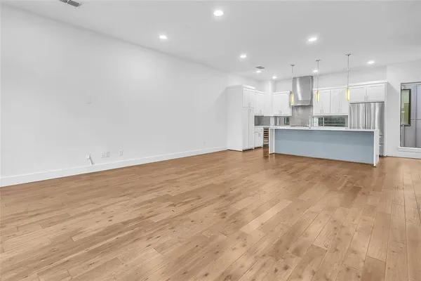 a view of kitchen with kitchen island a sink wooden floor and a living room view