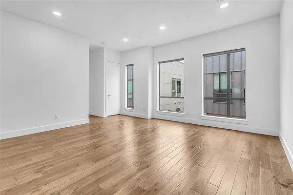 a view of an empty room with wooden floor and windows