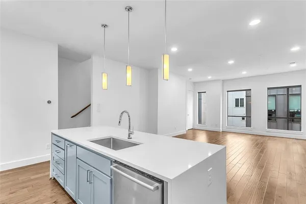 a kitchen with a sink a center island a wooden floor and a chandelier