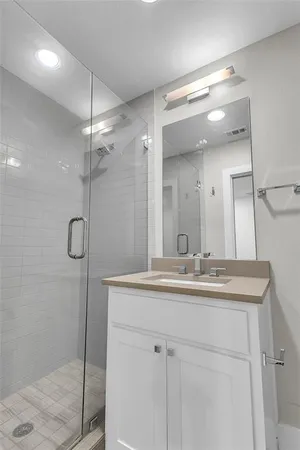 a bathroom with a shower sink vanity and mirror