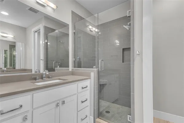 a bathroom with a shower sink vanity granite and a mirror
