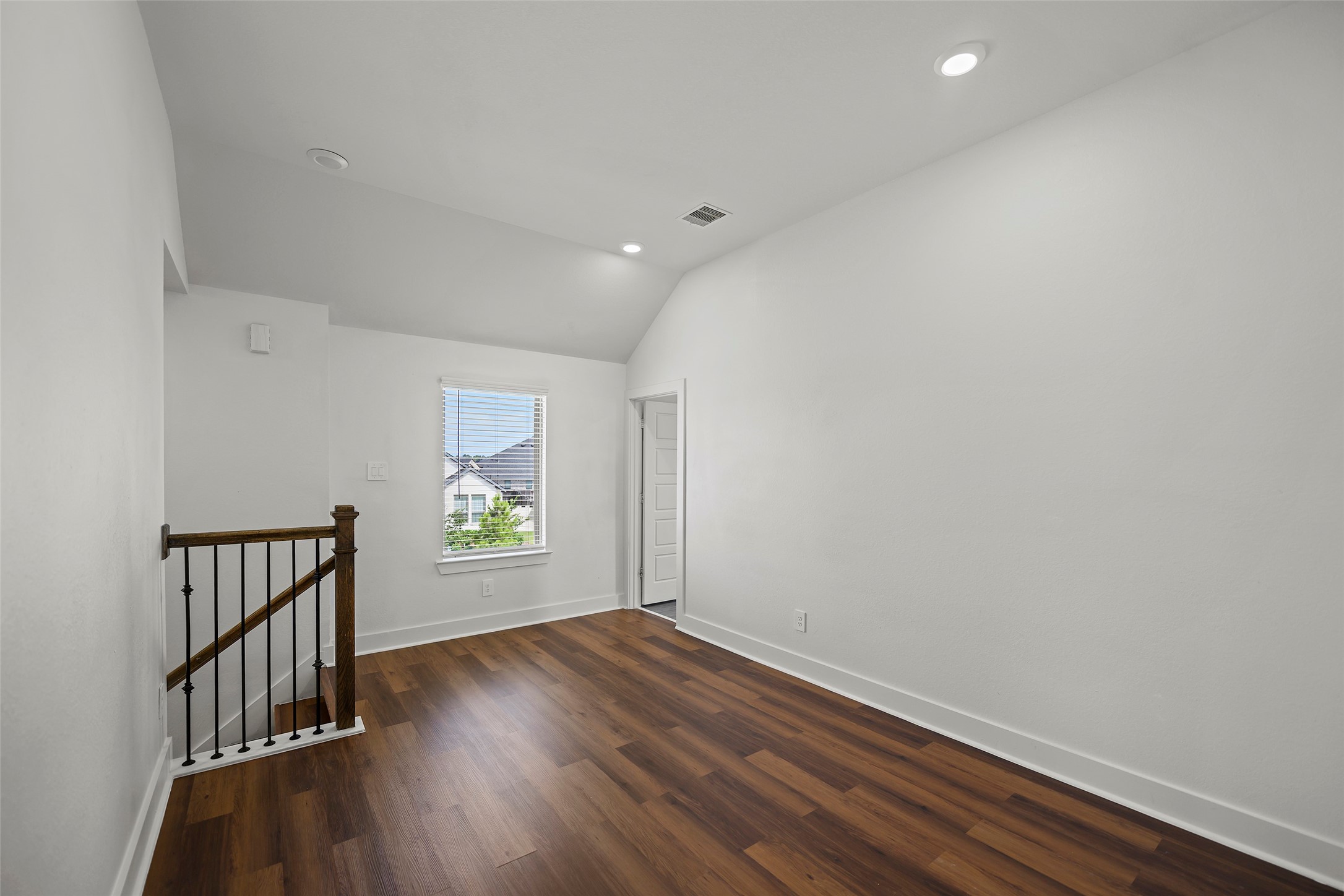 10603 Whitejacket Conroe, TX 77385 - Photo 14 of 42 This room features a cozy space with wood flooring, a small staircase with a decorative railing, and a window providing natural light. The walls are painted white, enhancing the room’s brightness, and there's a recessed light on the ceiling.