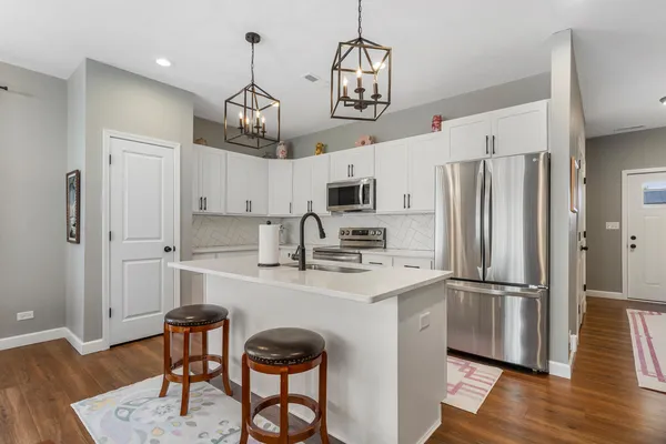 a kitchen with stainless steel appliances a refrigerator a sink dishwasher a stove and a dining table with wooden floor