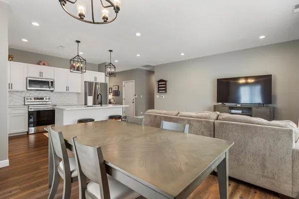 a living room with stainless steel appliances a table and chairs