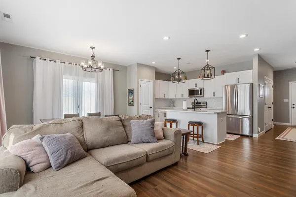 a living room with stainless steel appliances kitchen island granite countertop furniture and wooden floor