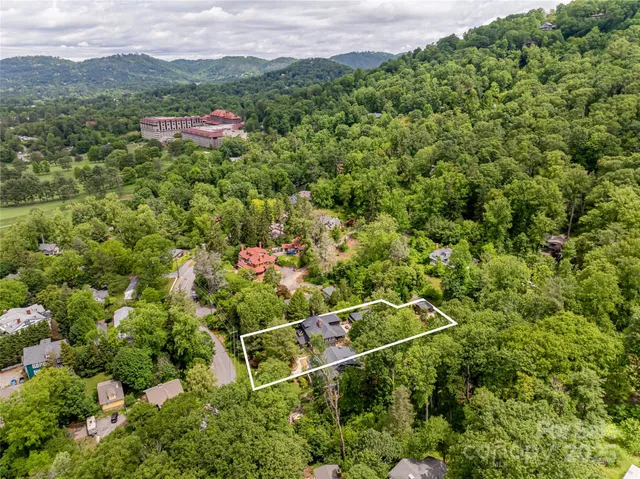 a view of a lush green forest with a house