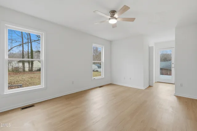 a view of an empty room with a window and wooden floor