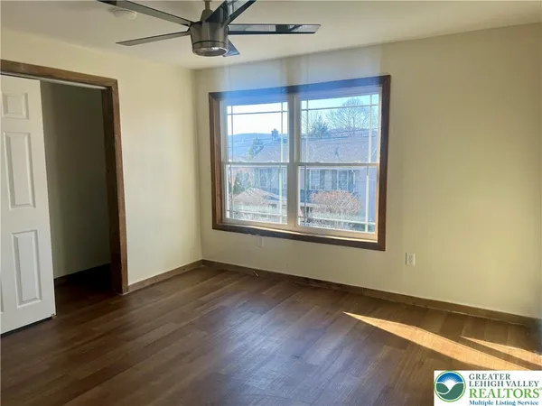 a view of an empty room with wooden floor and a window