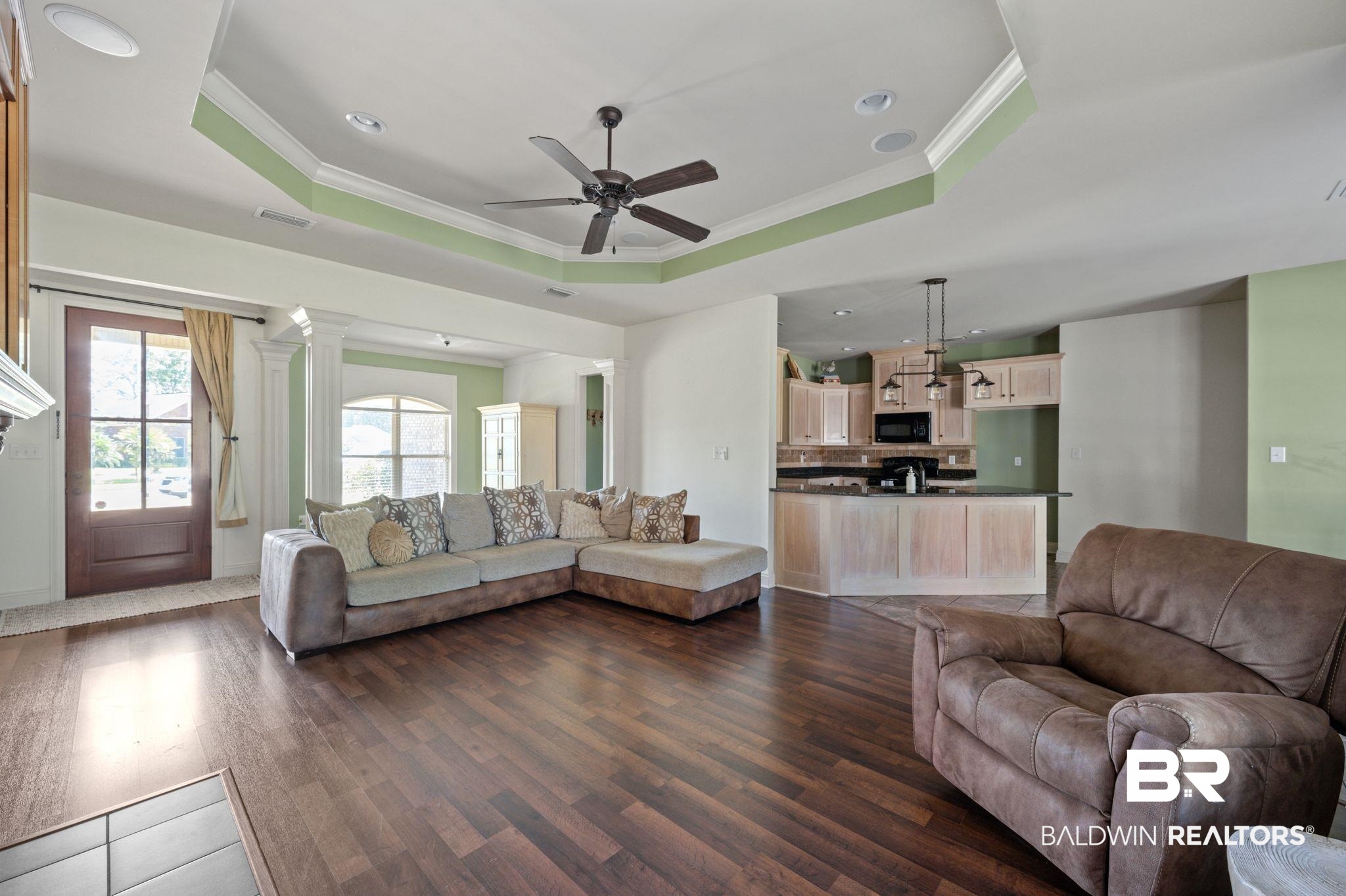 3879 Symphony Way West Semmes, AL 36575 - Photo 11 of 34 Living room with ornate columns, ornamental molding, wood-type flooring, ceiling fan, and a raised ceiling