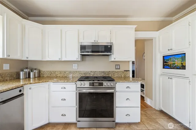 a kitchen with granite countertop white cabinets and stainless steel appliances
