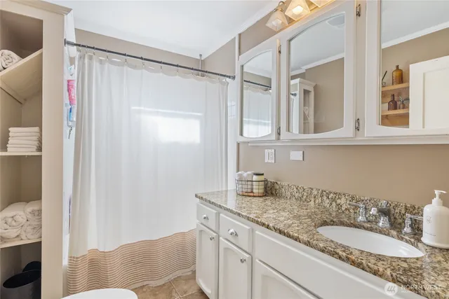 a bathroom with a granite countertop sink a mirror and shower