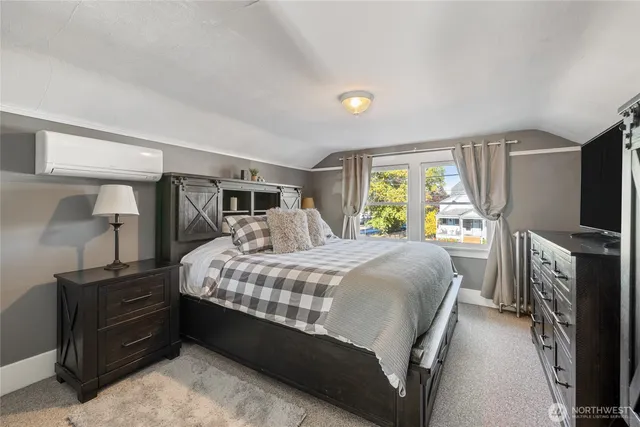 a bedroom with a bed and a flat tv screen on the dresser