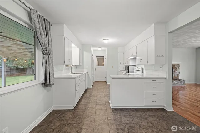 a large white kitchen with white cabinets and wooden floors