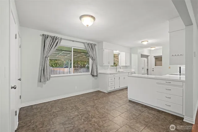 a large white kitchen with window and cabinets