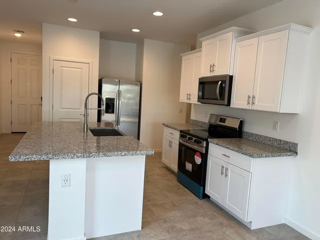 a kitchen with stainless steel appliances granite countertop a sink a stove and a refrigerator