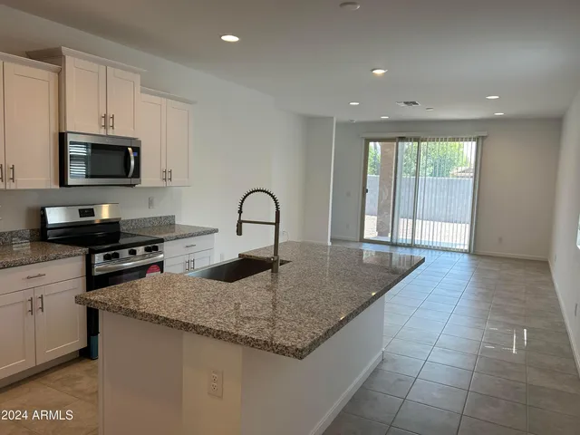 a kitchen with granite countertop a stove a sink and a microwave