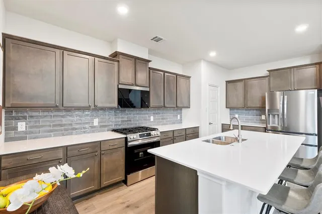 a kitchen with stainless steel appliances a sink a stove a refrigerator cabinets and a counter top space