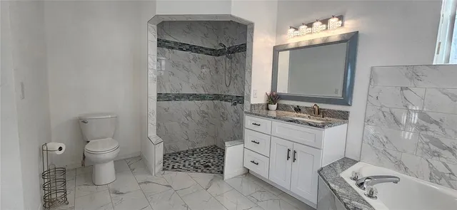 a spacious bathroom with a granite countertop sink toilet and shower