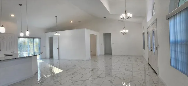 a view of a hallway with chandelier and a refrigerator