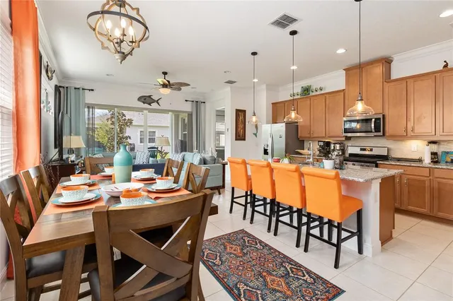 a room with stainless steel appliances kitchen island granite countertop a dining table chairs and a chandelier