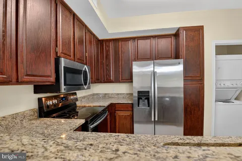 a kitchen with granite countertop wooden cabinets a refrigerator and a sink