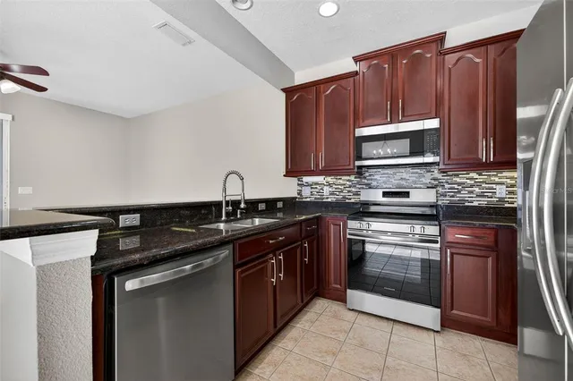 a kitchen with stainless steel appliances granite countertop a sink stove microwave and refrigerator