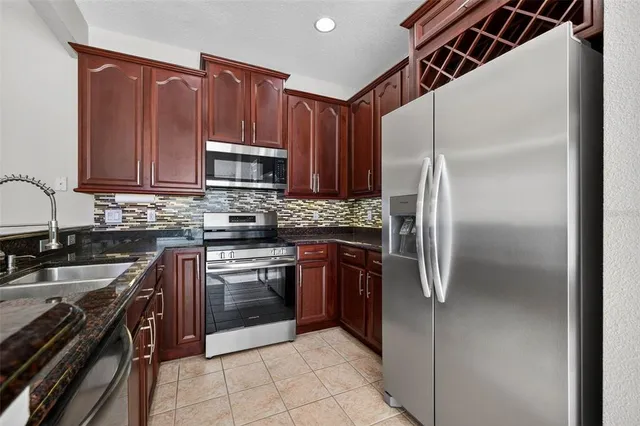 a kitchen with stainless steel appliances granite countertop a refrigerator stove and sink