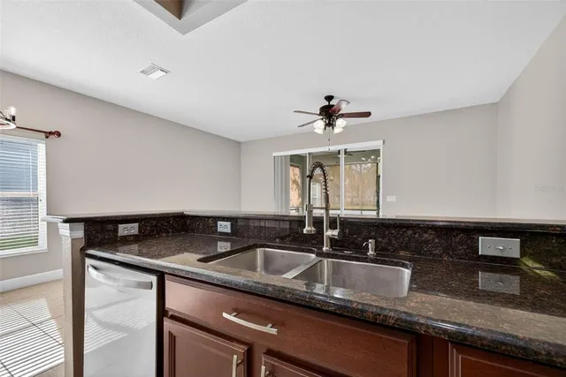 a kitchen with granite countertop a sink and a white wooden cabinets