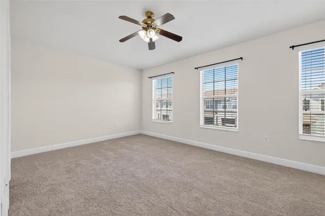 an empty room with windows and fan