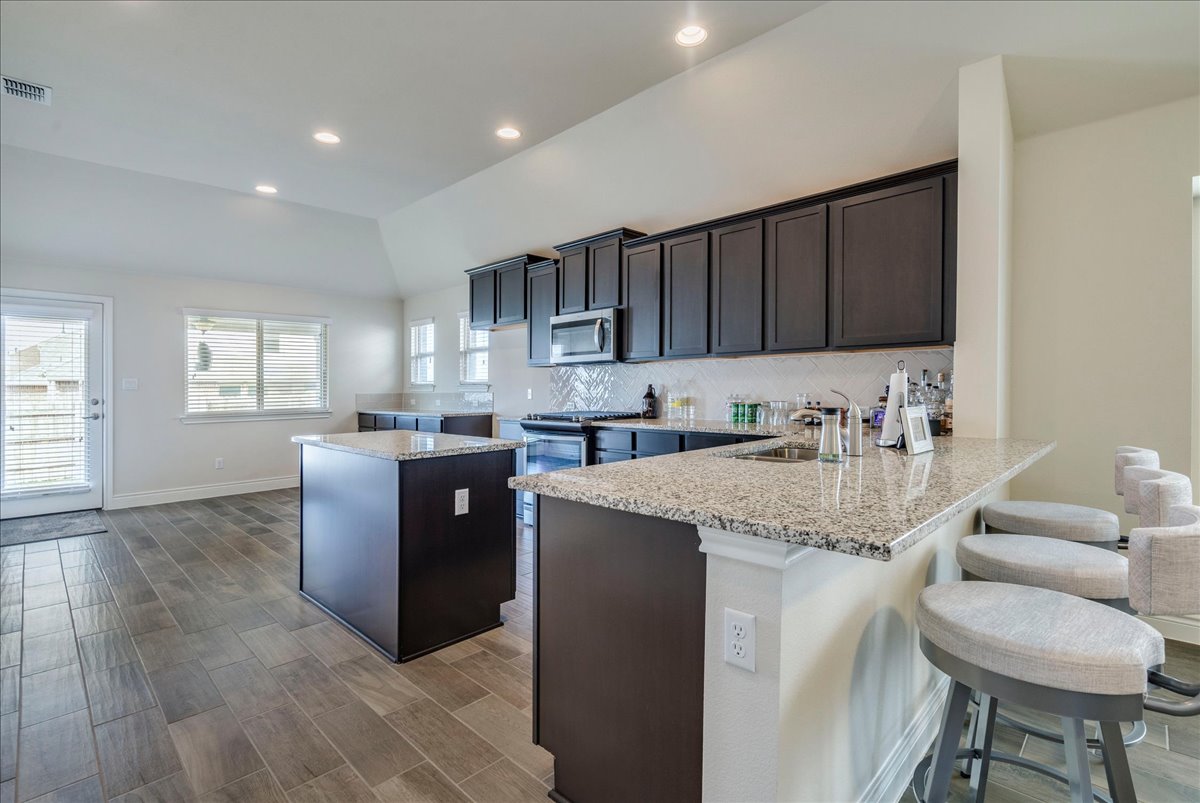 124 Compass Lane Kyle, TX 78640 - Photo 10 of 38 a kitchen with stainless steel appliances granite countertop a sink counter space and a refrigerator